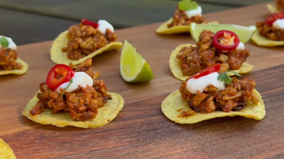 Mini tostadas, lettuce cups, flatwrap pinwheels and dipping sauces arranged on a wooden board