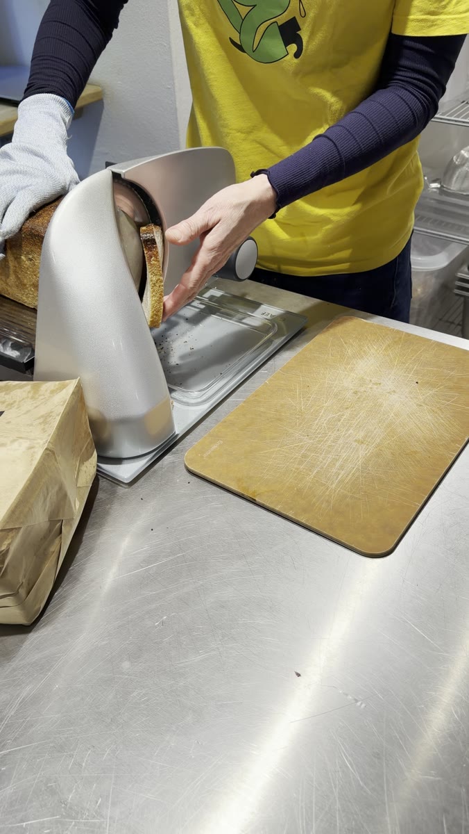 Sloppy Jo's team slicing a sourdough loaf to 12.5mm on a professional bread slicer at the deli